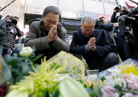 　大阪・北新地の放火殺人事件から４年となり、ビルの前で手を合わせる人たち＝１７日午前