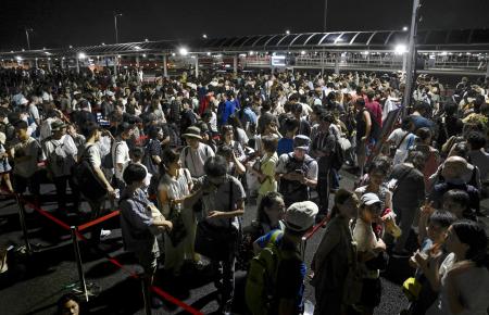 　大阪・関西万博会場にアクセスする地下鉄がトラブルで運転を見合わせ、会場のゲート前で並ぶ人たち＝２０２５年８月、大阪市此花区の夢洲