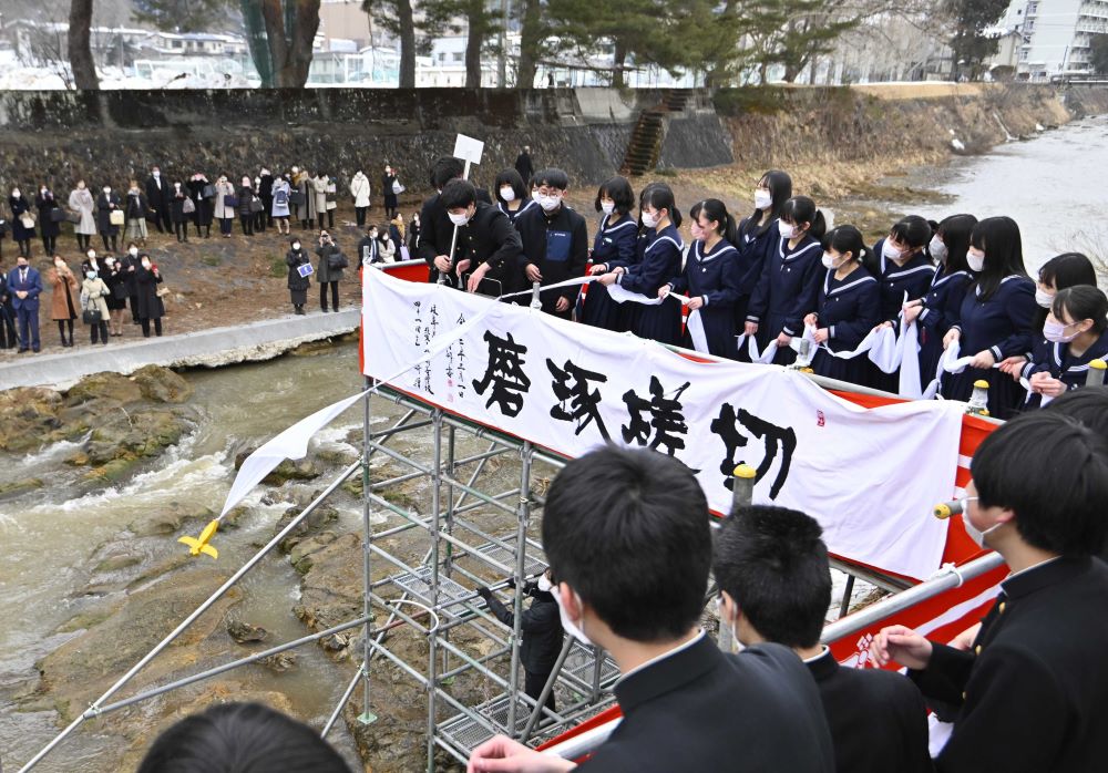 川べりの足場からスカーフを流す卒業生たち＝１日午後０時３９分、岐阜県高山市大新町、大八賀川