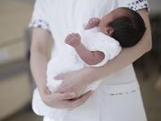 　病院で助産師に抱かれる新生児