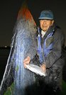 網に掛かったサツキマスを手にする小林大吉さん。この晩は網を網を流し、２匹を捕らえた＝今月１２日、大垣市、揖斐川