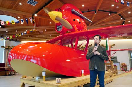 　リニューアルされたカフェ「ロタンダ風ケ丘」で、映画「紅の豚」に登場する赤い飛行艇を再現した作品を紹介するジブリパークの宮崎吾朗監督＝３１日午前、愛知県長久手市