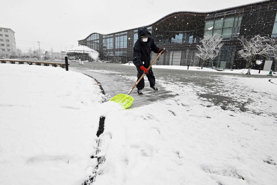 岐阜市の今季初積雪を受け広場の雪かきをする人＝２７日午前１０時１１分、岐阜市司町	