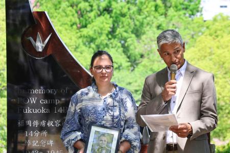 　外国人捕虜の追悼式でスピーチする遺族のクイントゥス・ファンデルベイルさん。左は娘のリサさん＝１０日午前、長崎市