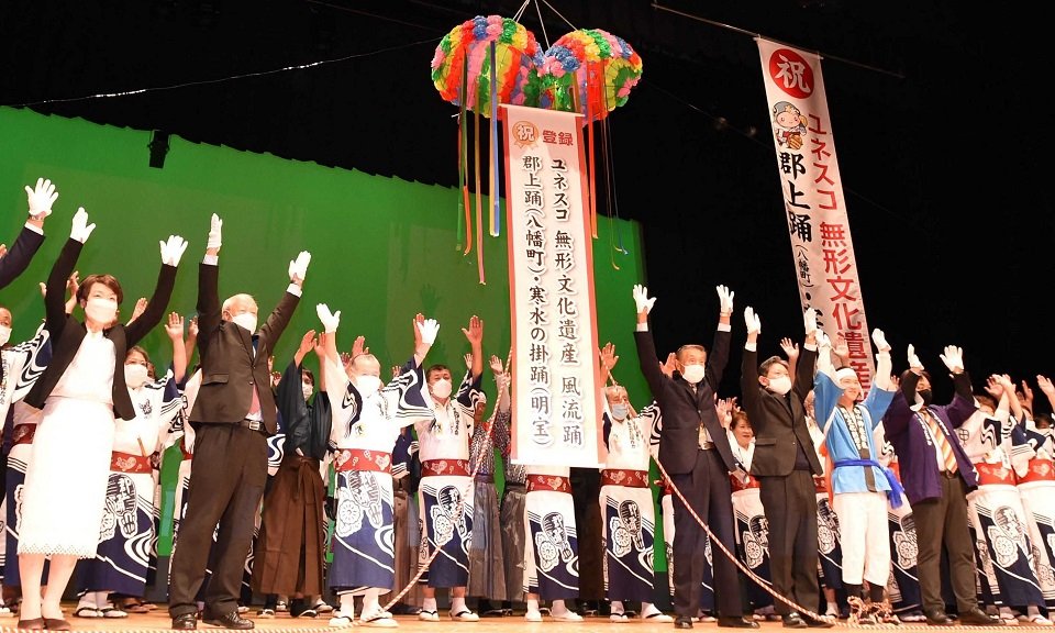 郡上踊と寒水の掛踊のユネスコ無形文化遺産登録が決まり、万歳三唱をして喜ぶ関係者ら＝３０日午後７時１３分、郡上市八幡町島谷、市総合文化センター