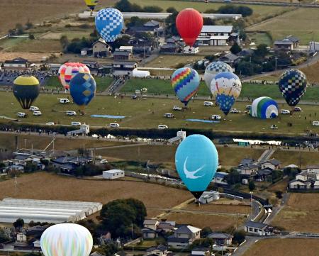 　佐賀インターナショナルバルーンフェスタが開幕し、浮かび上がる熱気球＝３０日午前、佐賀市（共同通信社ヘリから）