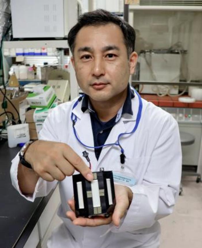 　開発した「遠紫外線」の装置を持つ徳島大の馬渡一諭講師＝７月、徳島市