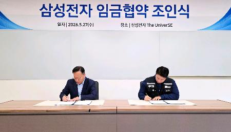 　２０２６年の賃金協約の調印式で署名する韓国の電機大手サムスン電子の労使＝２７日、韓国京畿道（サムスン電子提供、聯合＝共同）