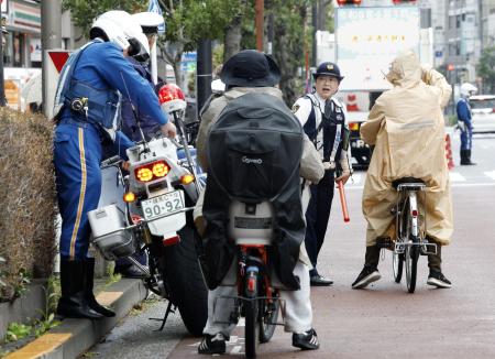 　自転車の青切符制度が始まり、東京都内で指導する警察官＝４月