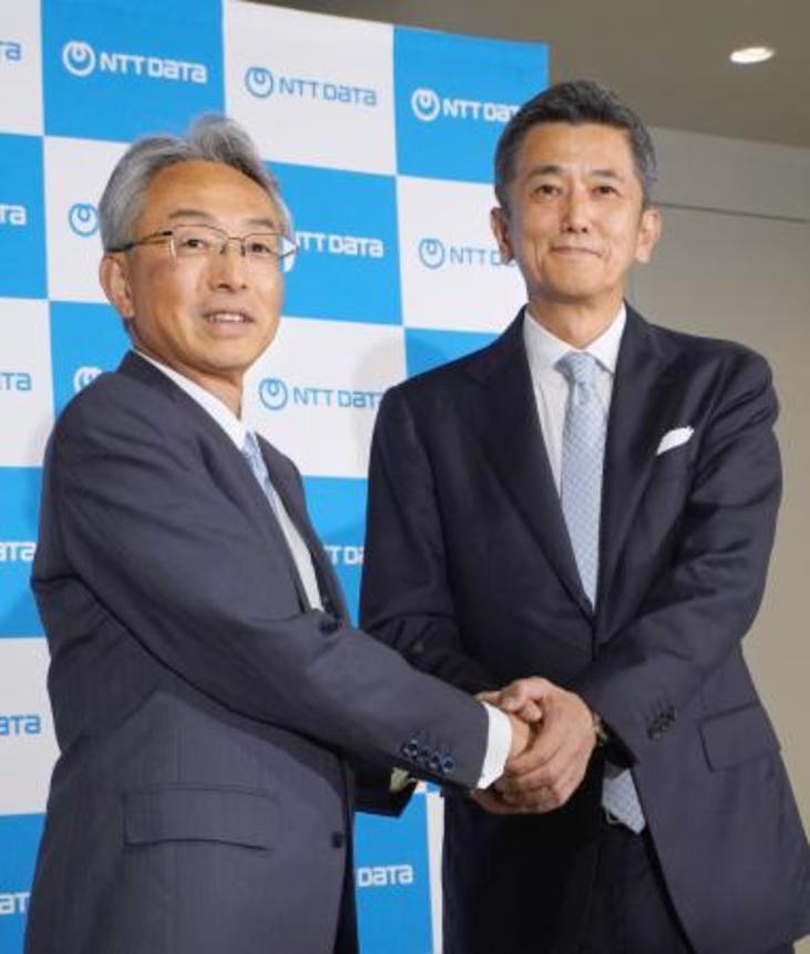 　握手を交わす、ＮＴＴデータグループの佐々木裕社長（左）とＮＴＴデータの鈴木正範社長＝２６日午後、東京都江東区