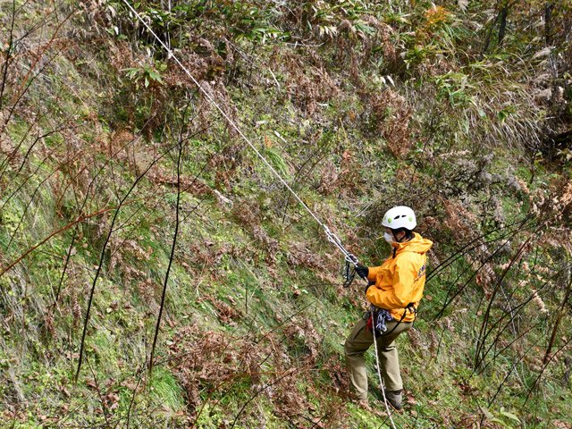 ロープを伝って斜面を下りる隊員＝高山市岩井町、国立乗鞍青少年交流の家