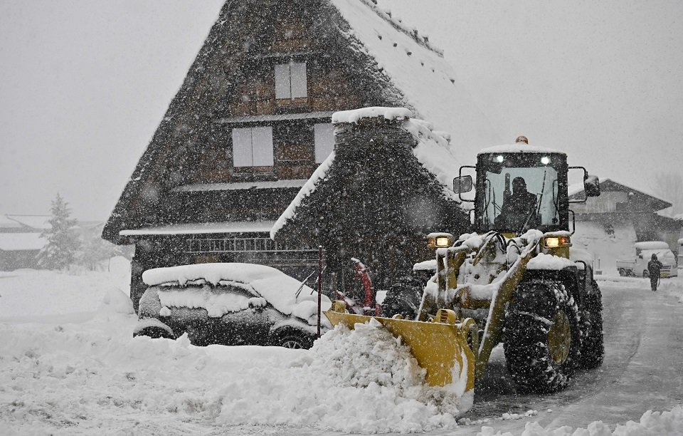 寒波に伴う雪が降る中、合掌造り集落内を除雪する重機＝２４日午後３時９分、大野郡白川村荻町