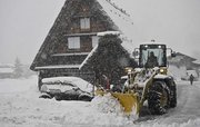寒波に伴う雪が降る中、合掌造り集落内を除雪する重機＝２４日午後３時９分、大野郡白川村荻町