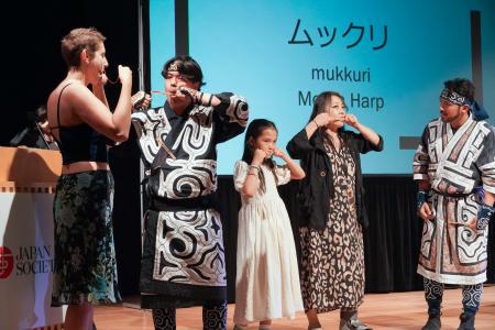 　アイヌ伝統の口琴「ムックリ」の演奏に挑戦する参加者＝２２日、米ニューヨーク（共同）