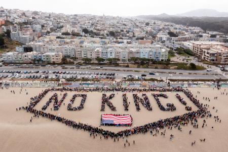 　砂浜に人文字で「ノー・キングス（王はいらない）」と抗議するデモ参加者＝１４日、サンフランシスコ（Ｓａｎｔｉａｇｏ　Ｍｅｊｉａ／サンフランシスコ・クロニクル提供・ＡＰ＝共同）