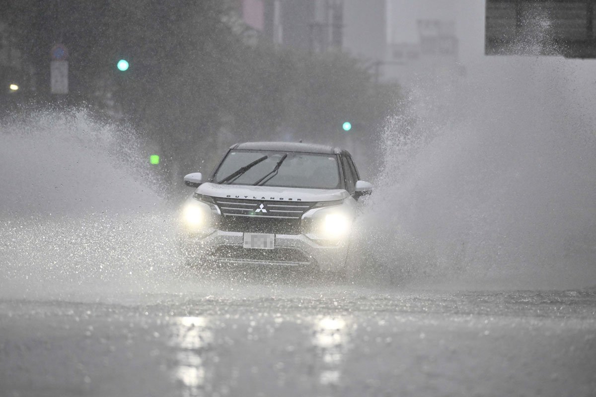 一部が冠水した道路を走る車（一部画像加工）＝８日午後３時２４分、岐阜市神田町（撮影・堀尚人）