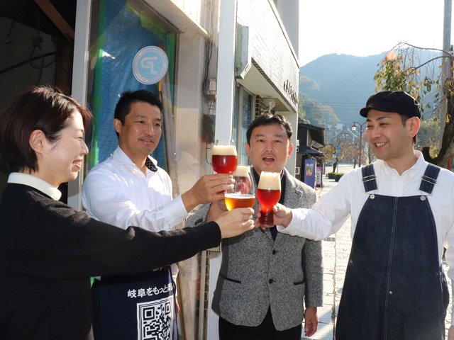 開店予定の建物の前でビールを片手に話し合う平塚悟さん（左から２人目）とまちづくり団体関係者＝岐阜市伊奈波通、伊奈波神社参道