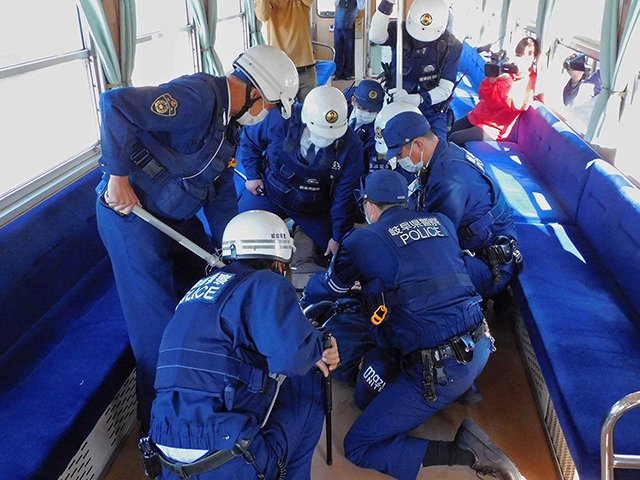 列車内で刃物男役を取り押さえる恵那署員ら＝８日午前、恵那市明智町、明知鉄道明智駅