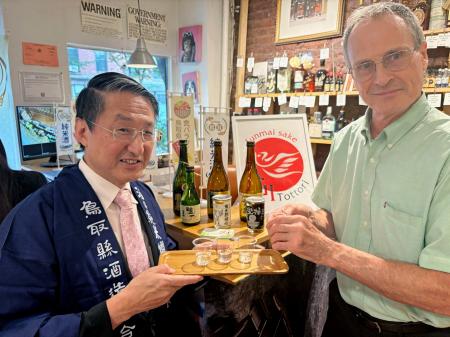 　米ニューヨーク・ブルックリンの酒店で行われた試飲会で鳥取県の日本酒を振る舞う平井伸治知事（左）＝２日（共同）