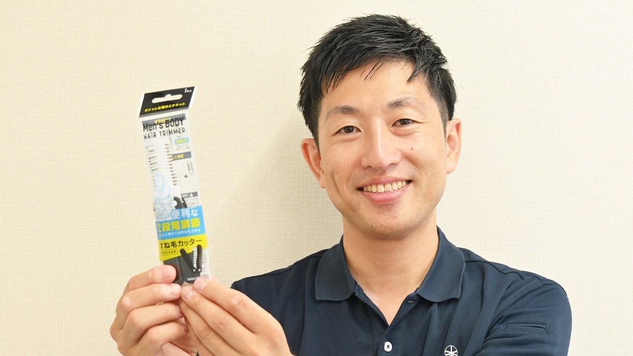 すね毛カッターを持つ熊田征純社長。自身も短パンをはくことが多いという。