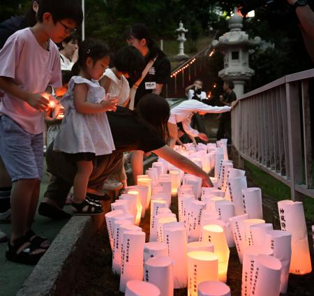 　戦死した特攻隊員を悼む集いで、灯籠に明かりをともす子どもたち＝２１日午後、鹿児島県鹿屋市