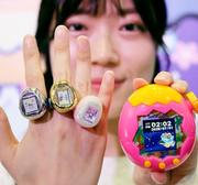 　「東京おもちゃショー２０２６」で発表されたバンダイの携帯型育成ゲームの新商品「たまごっち　リング」（左）。右は従来の商品＝２７日午前、東京都江東区