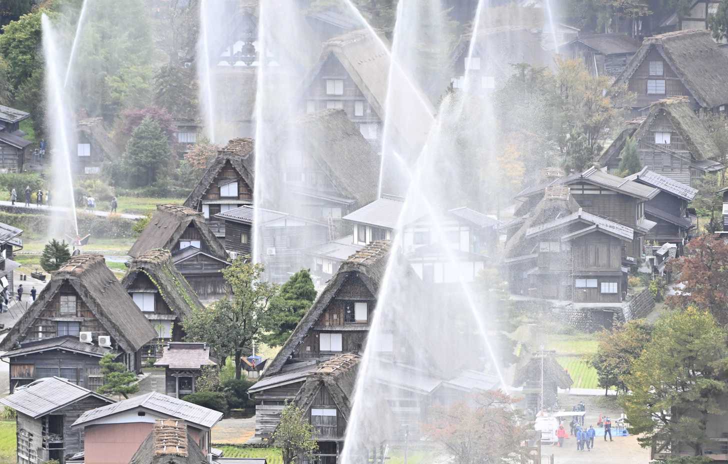合掌造り集落で行われた一斉放水訓練＝２９日午前８時３分、大野郡白川村荻町、天守閣展望台から望む