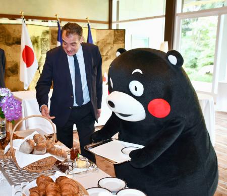 　フランスのセトン駐日大使（左）からフランスの朝食について説明を受ける「くまモン」＝２日午前、東京都港区