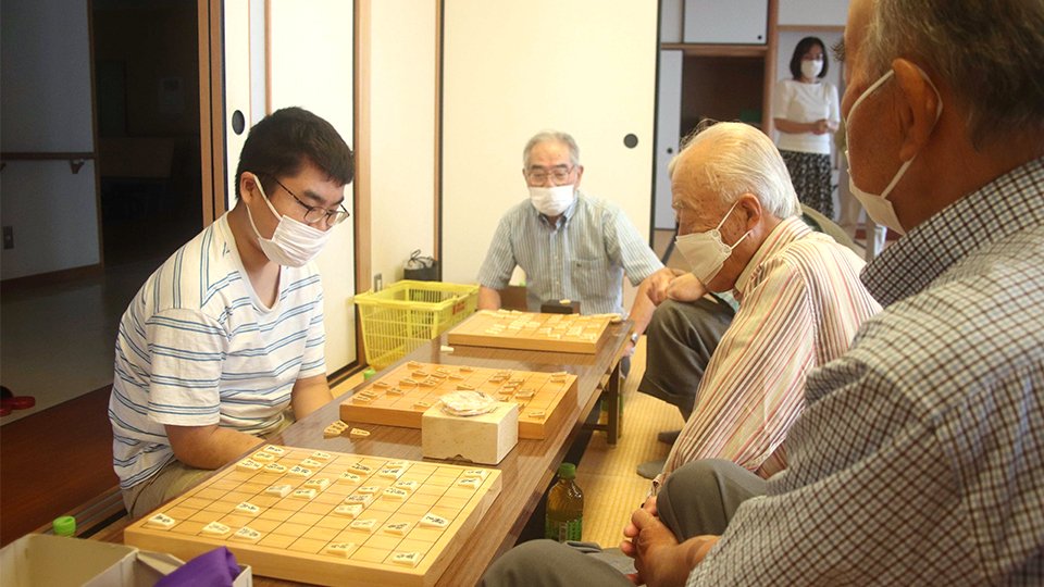 将棋サロンで３面指しをする高田明浩さん（左）＝６月２４日、各務原市三ツ池町、コミュニティ炉畑