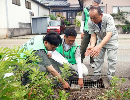 　土地家屋調査士と土地の境界を確認する中居正樹さん（右端）＝２２日午前、石川県内灘町