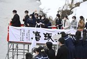 雪の残る川べりの足場からスカーフを流す卒業生たち＝１日午後０時２８分、岐阜県高山市大新町、大八賀川