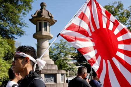 　１５日、靖国神社（東京・九段北）で旭日旗を掲げる人。（ロイター＝共同）