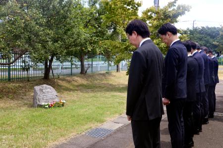 　小型プロペラ機の墜落事故から１０年となり、碑の前で黙とうする東京都港湾局の職員ら＝２６日午前、東京都調布市