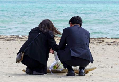 　沖縄県名護市辺野古の浜に花を手向ける武石知華さんの両親＝１８日午後