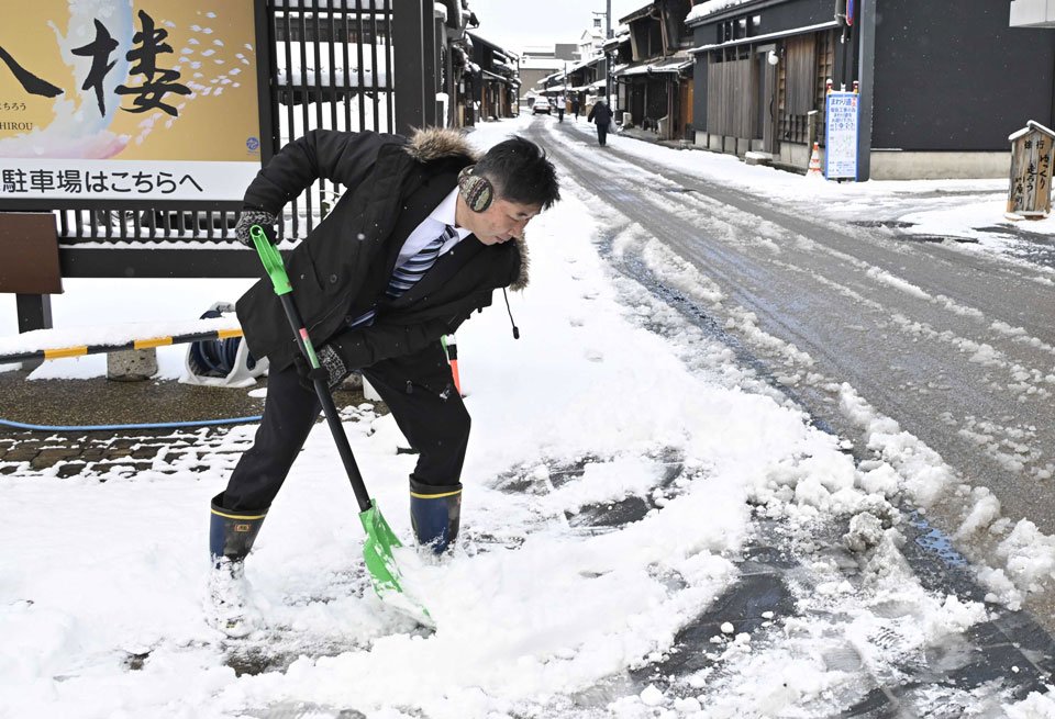 雪かきをする旅館関係者＝８日午前８時１３分、岐阜市湊町
