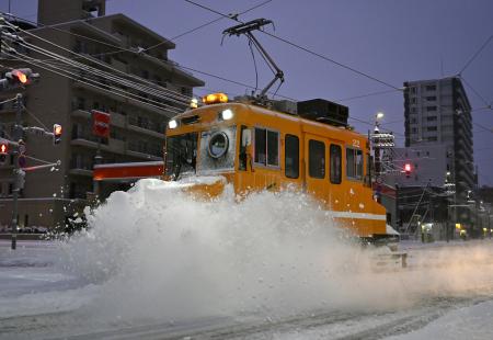 　今季初めて出動し、軌道に積もった雪を掃き飛ばす「ササラ電車」＝８日午前６時３分、札幌市中央区