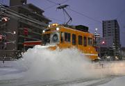 　今季初めて出動し、軌道に積もった雪を掃き飛ばす「ササラ電車」＝８日午前６時３分、札幌市中央区