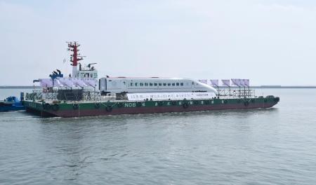 　熊本港を船で出発する九州新幹線つばめの車両＝２９日午後、熊本市