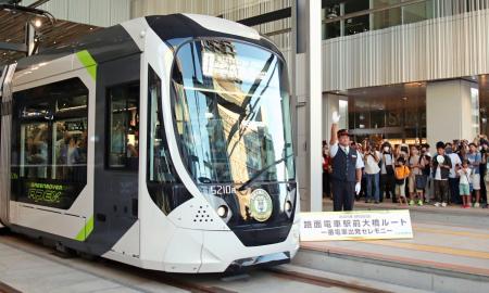 　広島電鉄の新線「駅前大橋線」が開業し、広島駅電停を出発する一番電車＝３日早朝、広島市南区