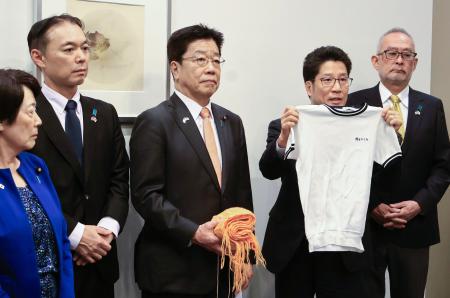 　訪米に持参した横田めぐみさんの体操服を示し、報道陣の取材に応じる拉致被害者家族会代表の横田拓也さん（右から２人目）ら＝２５日午後、羽田空港（代表撮影）