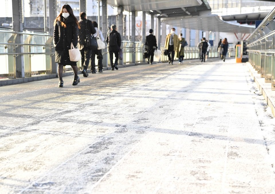雪が積もった箇所を避けて歩く人たち＝岐阜市橋本町、ＪＲ岐阜駅前
