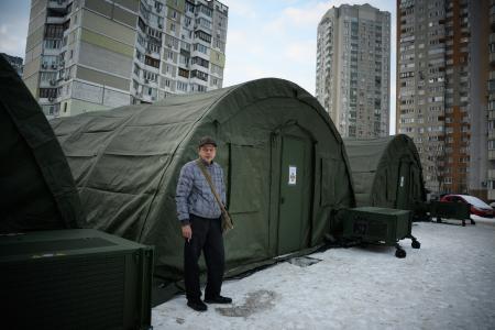 　２５日、ウクライナ・キーウに設けられた緊急暖房設備の前に立つ地元住民（ゲッティ＝共同）