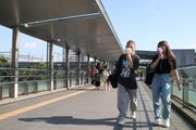 うだる暑さの中、ミニ扇風機で涼を取りながら歩く女性＝２６日午後４時、岐阜市橋本町、ＪＲ岐阜駅北口