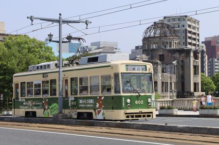 　原爆ドーム（右奥）の近くを走る広島電鉄の路面電車＝１３日午後、広島市中区
