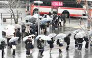 雪が降る中、バスを待つ学生ら＝５日午前７時４１分、岐阜市橋本町