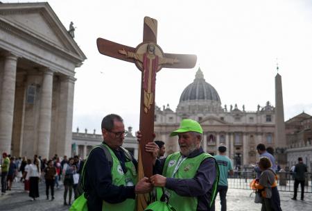 　次期ローマ教皇を決めるコンクラーベを前に、バチカンのサンピエトロ広場近くで十字架を掲げる人ら＝５日（ロイター＝共同）