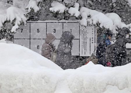 　雪でかすむ衆院選候補者のポスター掲示板＝２６日、札幌市