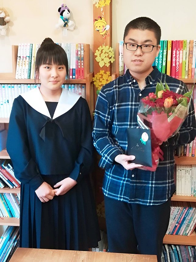 岩佐美帆子現女流１級（左）から四段昇段を祝う花束を贈られた高田明浩さん＝２０２１年３月、各務原市鵜沼朝日町、文聞分
