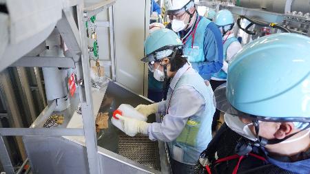　東電福島第１原発構内で、海水で希釈する前の処理水を採取する中国の専門家ら＝１７日（東電提供）