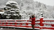 高山市の赤い中橋で雪景色を撮影する人＝１８日午前１０時５２分